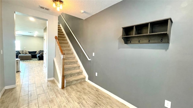 staircase with hardwood / wood-style flooring and a textured ceiling