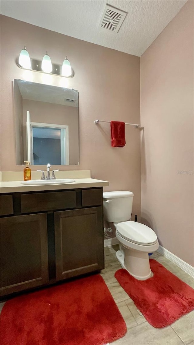 bathroom featuring a textured ceiling, vanity, and toilet