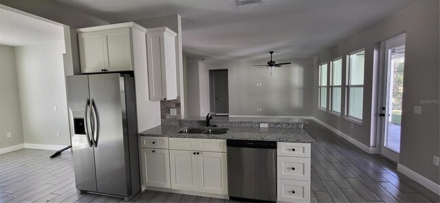 kitchen featuring wood tiled floor, a peninsula, a sink, white cabinets, and appliances with stainless steel finishes