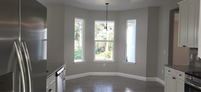 kitchen with white cabinetry, dark stone counters, baseboards, and appliances with stainless steel finishes