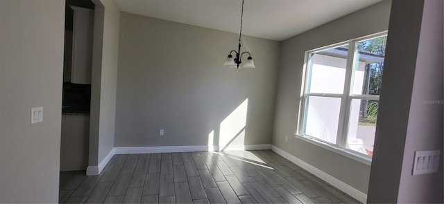 unfurnished room with a chandelier, plenty of natural light, and dark hardwood / wood-style floors