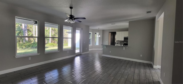 unfurnished living room with visible vents, baseboards, ceiling fan, and dark wood-style flooring