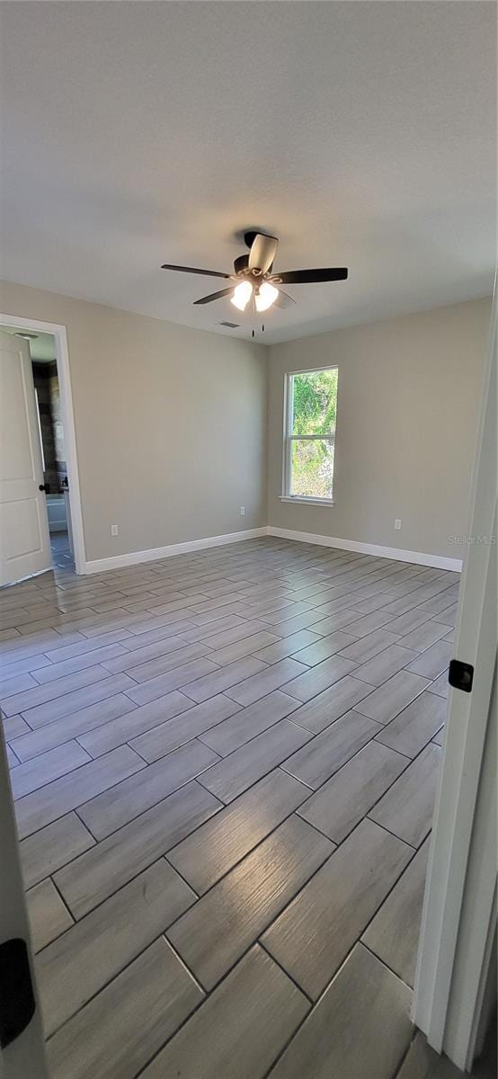 empty room featuring a ceiling fan, baseboards, and wood finished floors