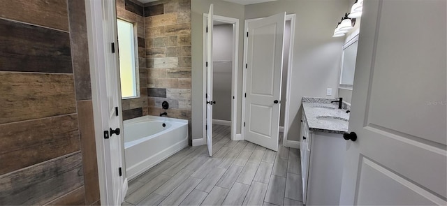 full bath featuring wood finish floors, baseboards, a garden tub, and vanity