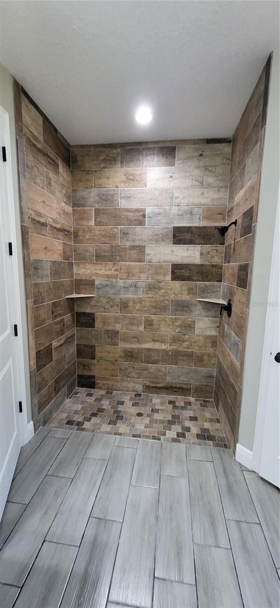 bathroom with a tile shower and a textured ceiling