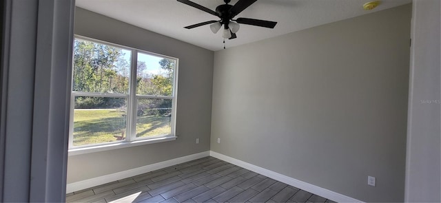 unfurnished room featuring baseboards, ceiling fan, and dark wood finished floors