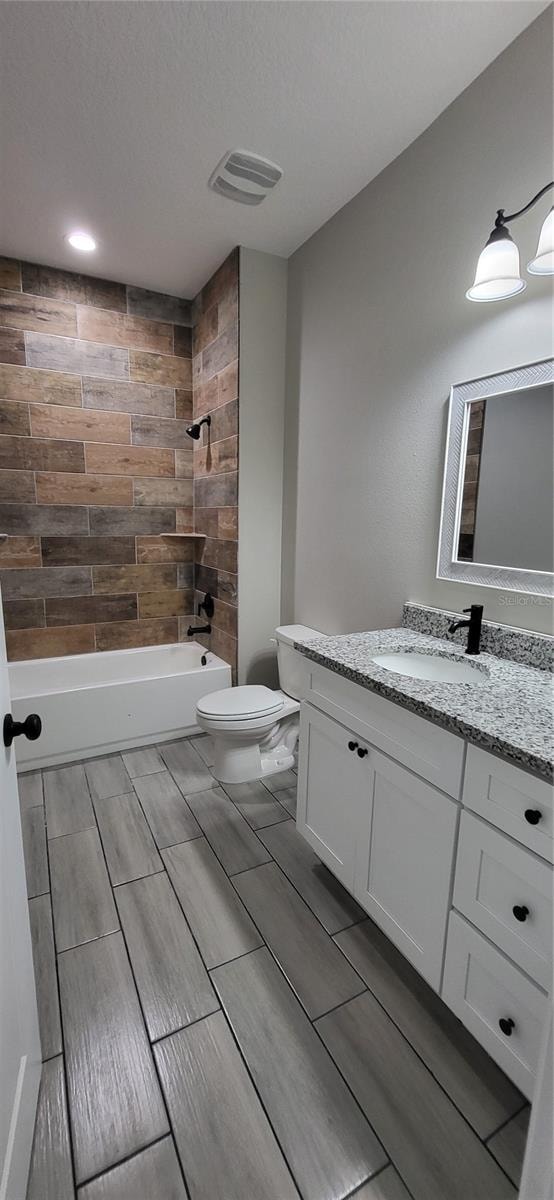 full bathroom featuring vanity, toilet, and tiled shower / bath combo