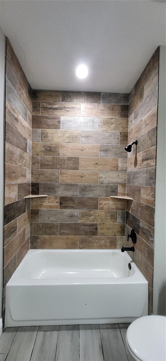 bathroom with tiled shower / bath and toilet