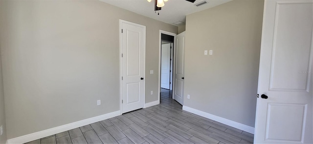 unfurnished bedroom with ceiling fan, baseboards, visible vents, and wood tiled floor