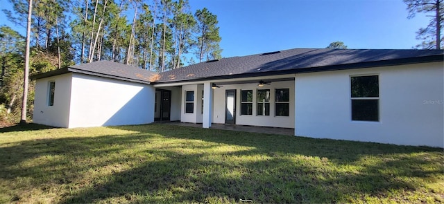 rear view of house with a yard, stucco siding, a patio, and ceiling fan