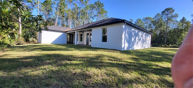 view of front of property with stucco siding, a ceiling fan, and a front yard