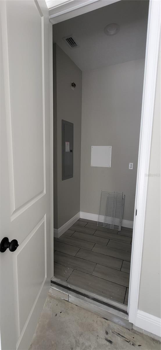 interior space featuring electric panel, visible vents, baseboards, and wood finished floors