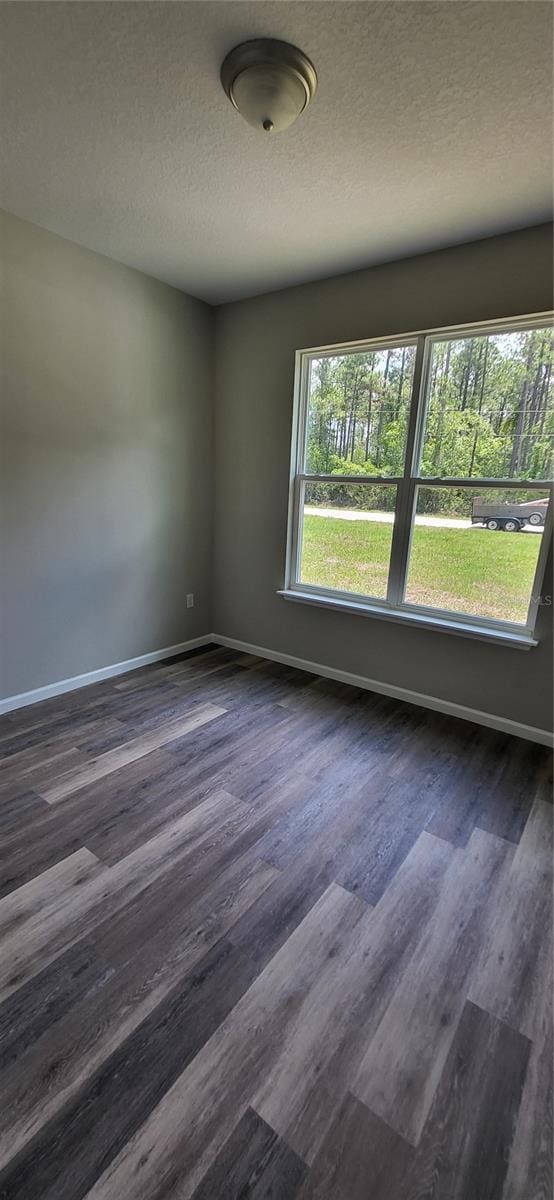 spare room with a textured ceiling and dark wood-type flooring