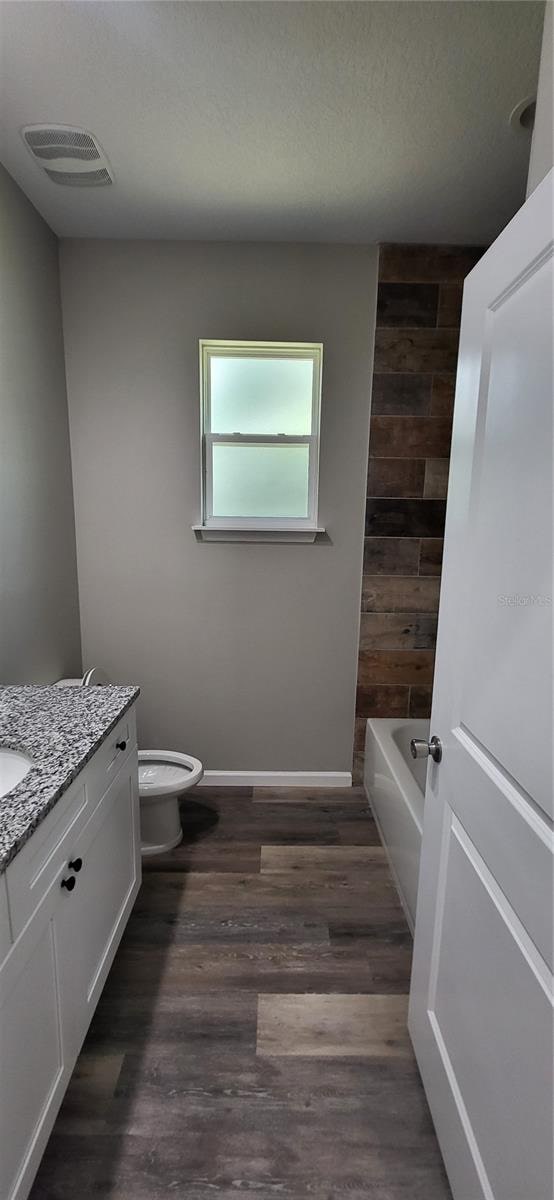 full bathroom featuring toilet, vanity, bathing tub / shower combination, and hardwood / wood-style floors