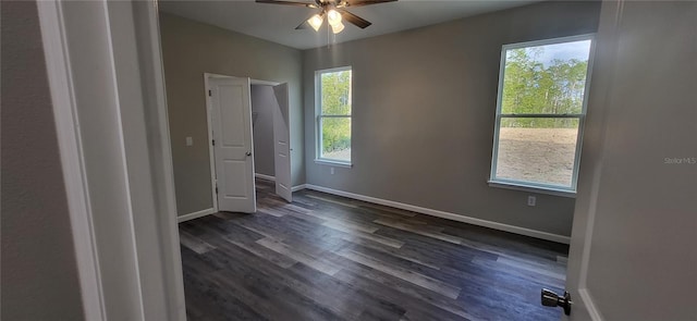 unfurnished bedroom featuring dark wood-type flooring, ceiling fan, and multiple windows