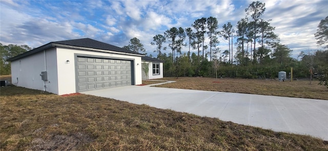 exterior space featuring a garage, a lawn, and central air condition unit