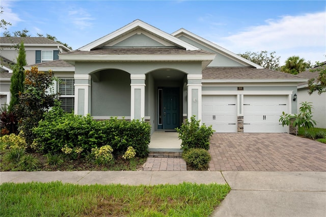 890 Terrapin Dr, Debary, FL 32713 - view of front of property featuring roof with shingles, stucco siding, decorative driveway, an attached garage, and a porch