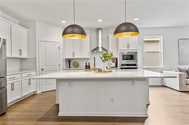 890 Terrapin Dr, Debary, FL 32713 - kitchen featuring wall chimney range hood, light countertops, appliances with stainless steel finishes, and wood finished floors