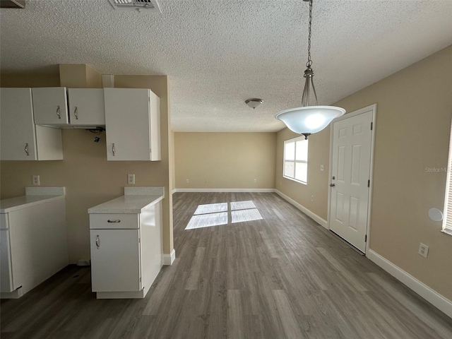 kitchen with white cabinetry, hardwood / wood-style floors, a textured ceiling, and hanging light fixtures