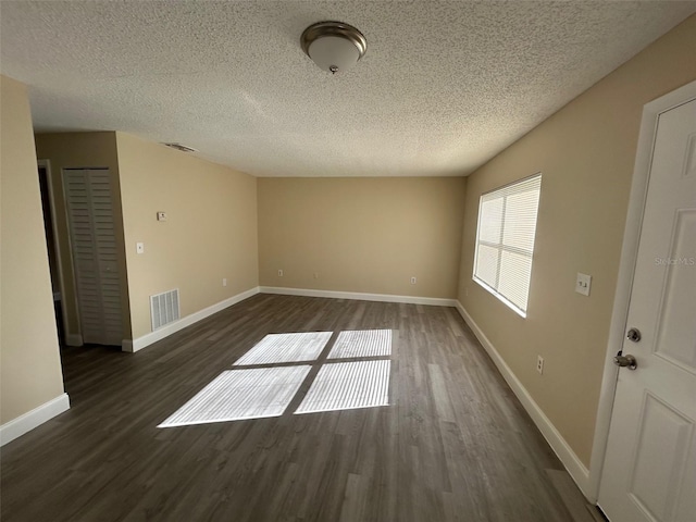 empty room with dark hardwood / wood-style floors and a textured ceiling