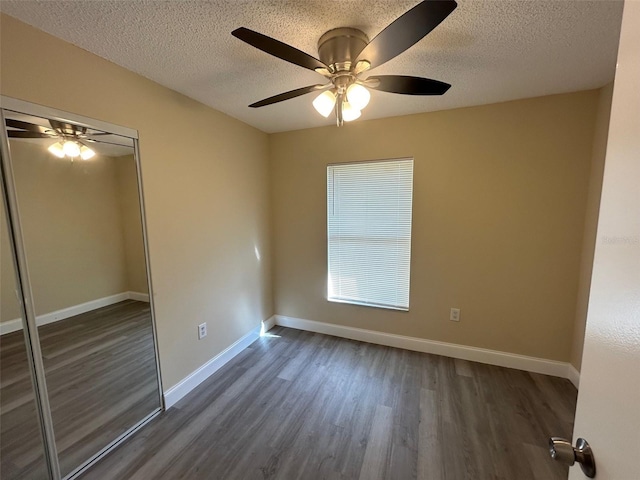 unfurnished bedroom featuring dark hardwood / wood-style flooring, a closet, a textured ceiling, and ceiling fan