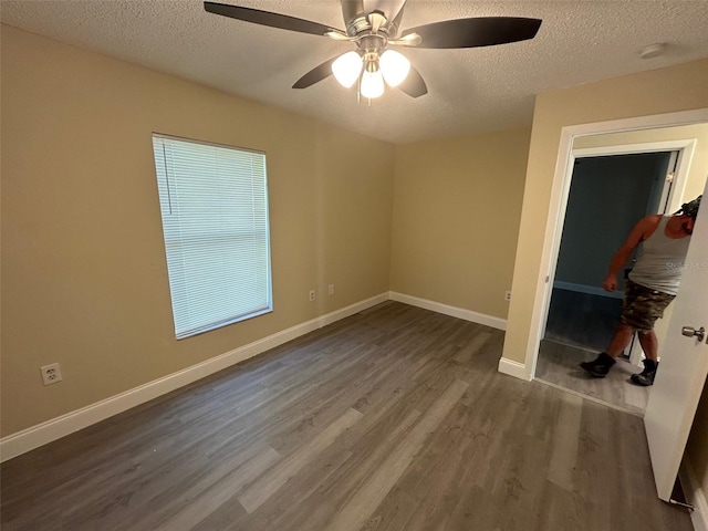 unfurnished bedroom with dark wood-type flooring, a textured ceiling, a closet, and ceiling fan