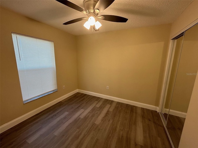 unfurnished bedroom with a textured ceiling, dark hardwood / wood-style floors, a closet, and ceiling fan