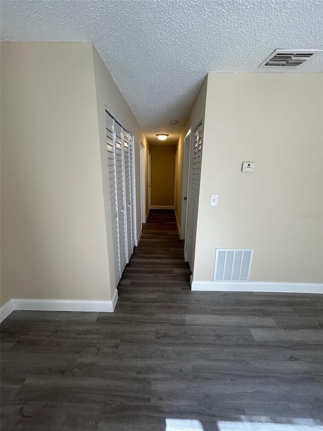 hallway featuring dark hardwood / wood-style floors and a textured ceiling