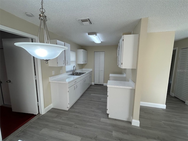 kitchen featuring sink, white cabinetry, decorative light fixtures, and light hardwood / wood-style floors