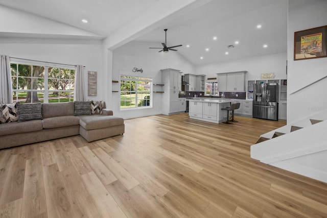 living room featuring high vaulted ceiling, light hardwood / wood-style floors, and ceiling fan