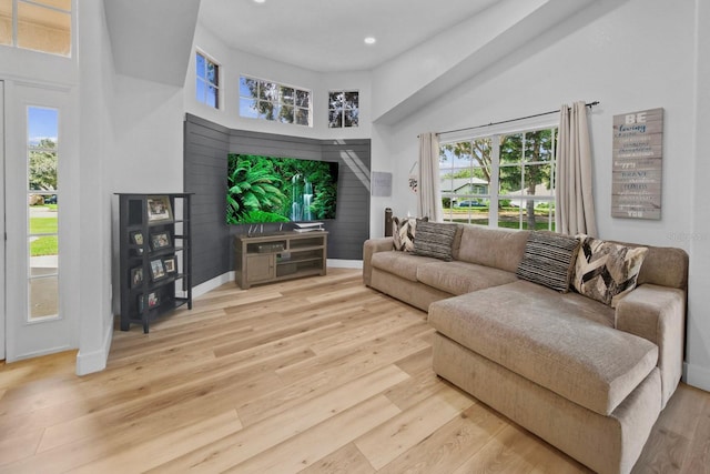 living room with a high ceiling, a healthy amount of sunlight, and light hardwood / wood-style floors