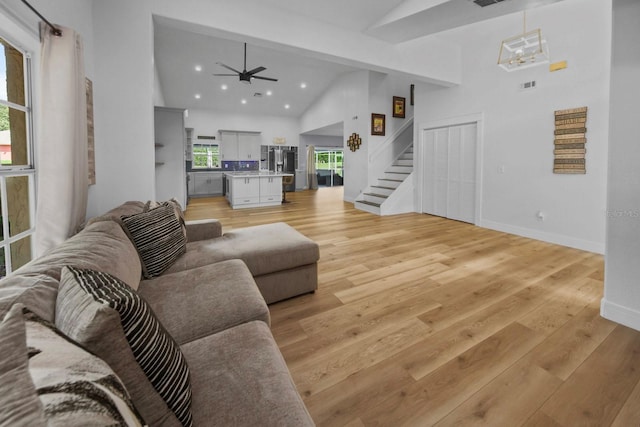 living room featuring high vaulted ceiling, light hardwood / wood-style floors, and ceiling fan