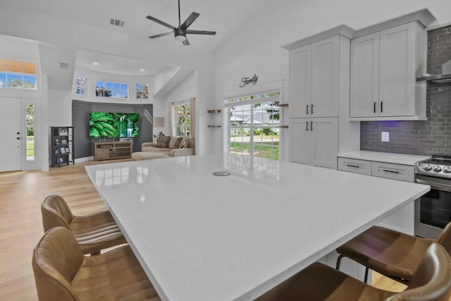 kitchen featuring gray cabinetry, a large island, stainless steel electric stove, and a kitchen bar