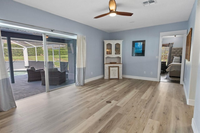 unfurnished living room featuring ceiling fan, light wood-type flooring, and a wealth of natural light