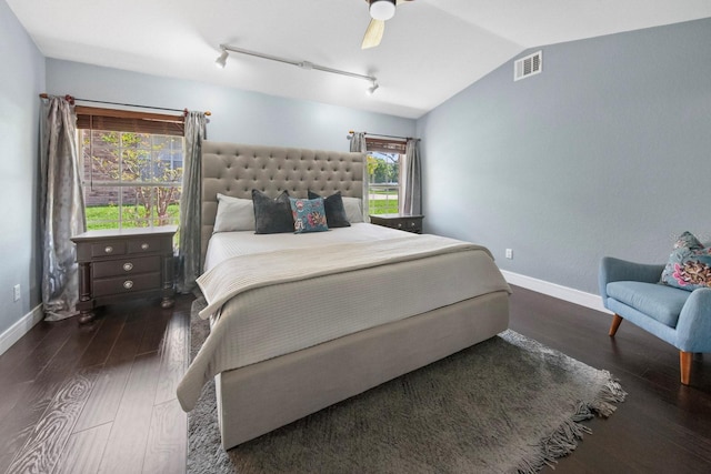 bedroom with dark hardwood / wood-style flooring, vaulted ceiling, rail lighting, and ceiling fan