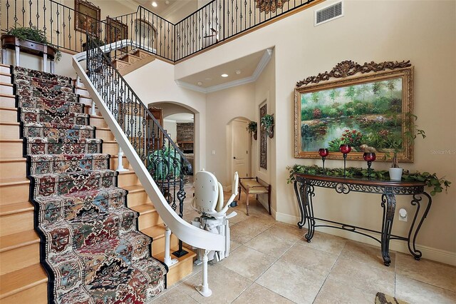 212 Crestrun Loop, Leesburg, FL 34748 - stairs with arched walkways, crown molding, a high ceiling, baseboards, and tile patterned floors