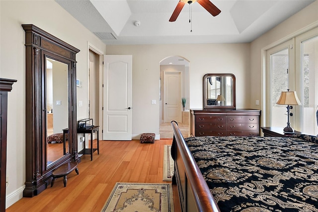 212 Crestrun Loop, Leesburg, FL 34748 - bedroom featuring light wood-style floors, arched walkways, baseboards, and a tray ceiling