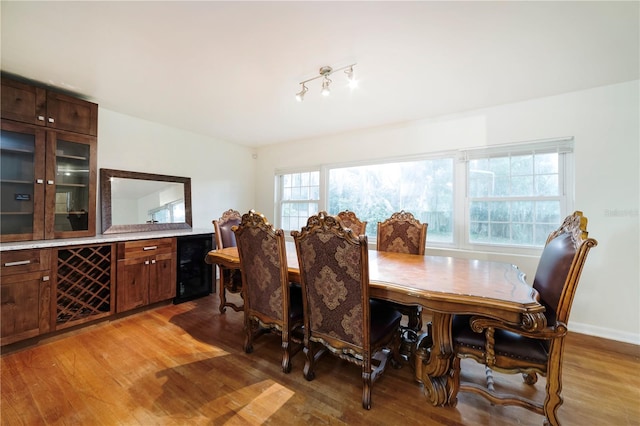 dining space featuring beverage cooler, light wood-type flooring, and a healthy amount of sunlight