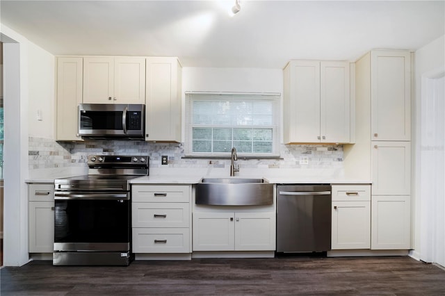 kitchen with tasteful backsplash, dark wood-type flooring, sink, stainless steel appliances, and white cabinetry