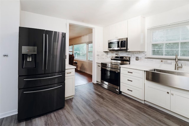 kitchen featuring appliances with stainless steel finishes, dark wood-type flooring, sink, and white cabinets