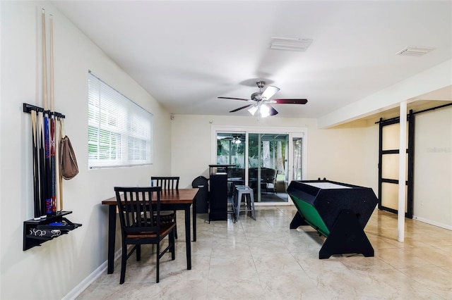 recreation room with ceiling fan and a barn door