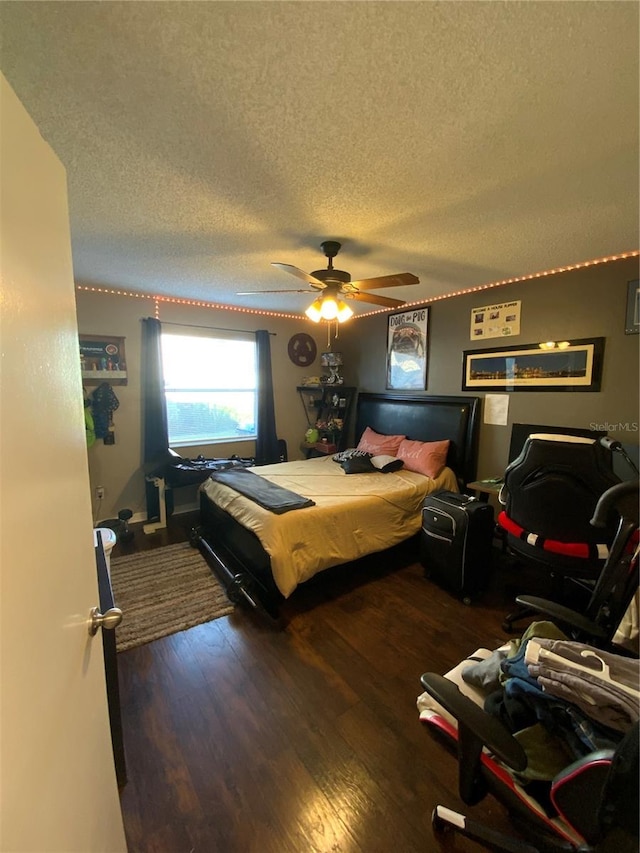 bedroom featuring dark hardwood / wood-style flooring, a textured ceiling, and ceiling fan