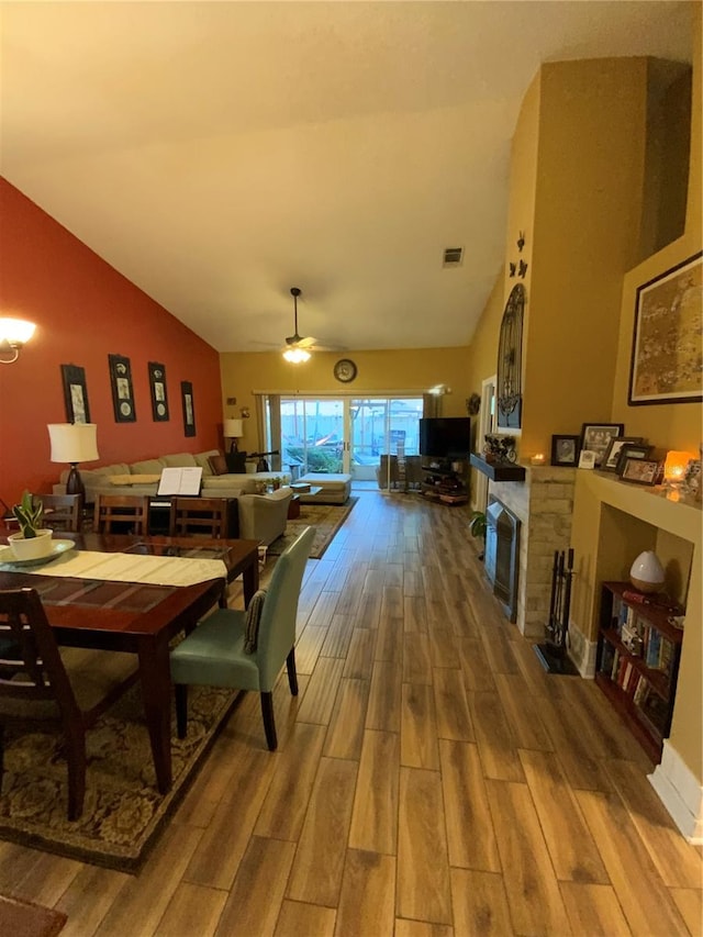 dining area with hardwood / wood-style floors, high vaulted ceiling, and ceiling fan