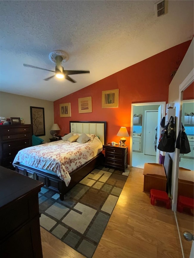 bedroom with light hardwood / wood-style flooring, a textured ceiling, lofted ceiling, and ceiling fan