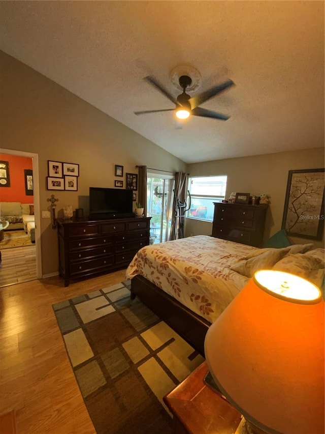 bedroom with a textured ceiling, vaulted ceiling, light wood-type flooring, and ceiling fan