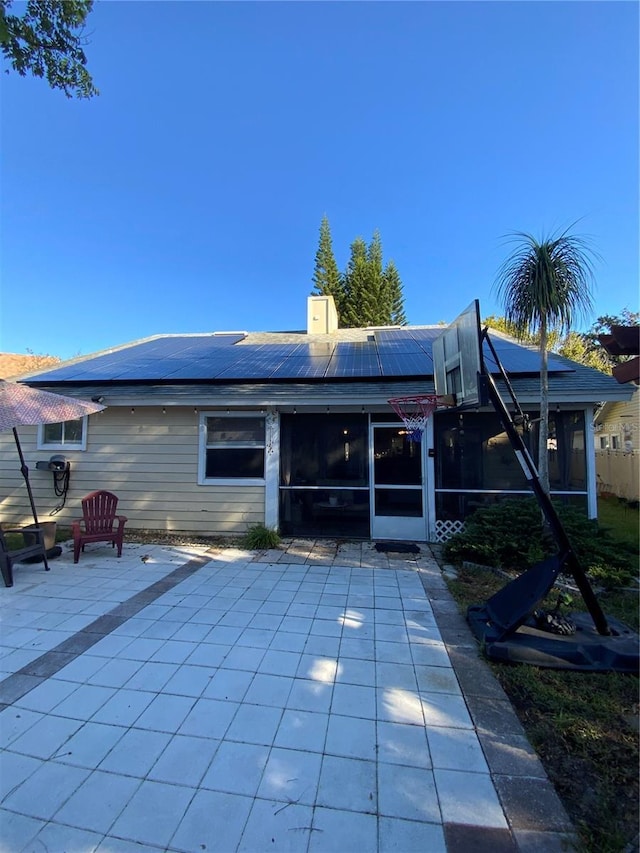 2939 Falling Tree Cir, Orlando, FL 32837 - rear view of house with a sunroom, roof mounted solar panels, a chimney, and a patio