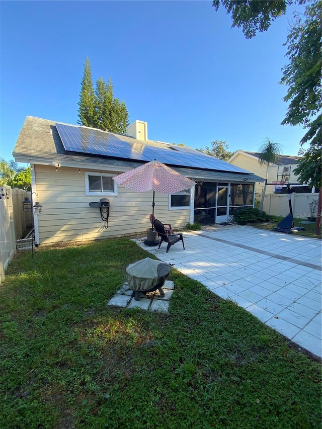 rear view of house featuring a yard, solar panels, a patio area, and a sunroom