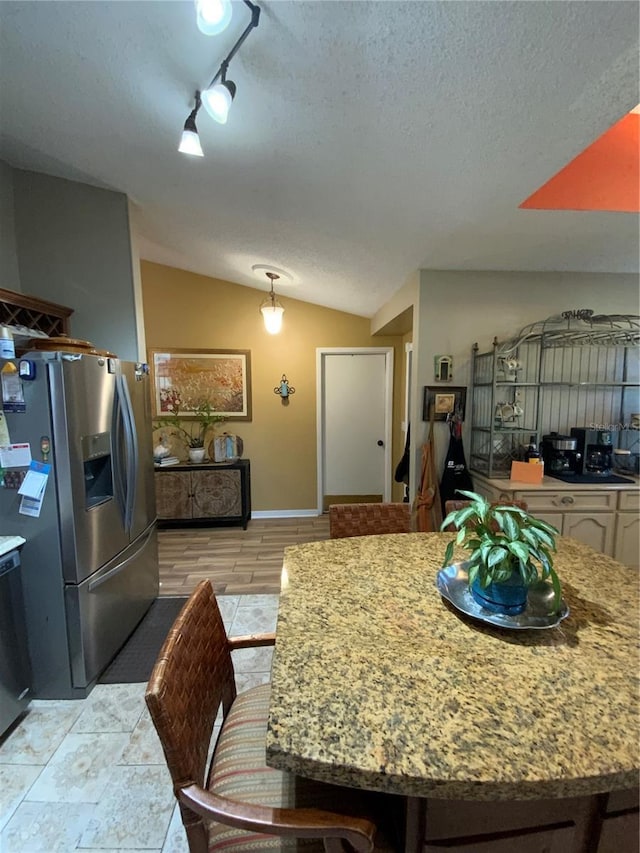 kitchen featuring vaulted ceiling, stainless steel fridge with ice dispenser, a textured ceiling, and light wood-type flooring