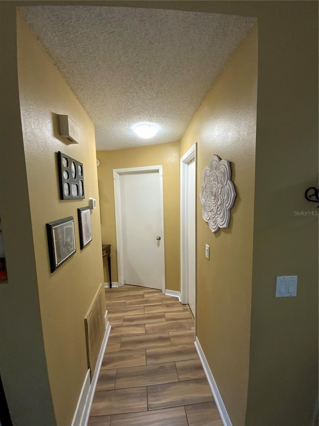 corridor featuring a textured ceiling and light wood-type flooring