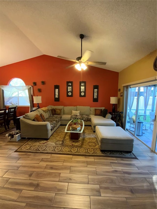 living room with a textured ceiling, wood-type flooring, lofted ceiling, and plenty of natural light